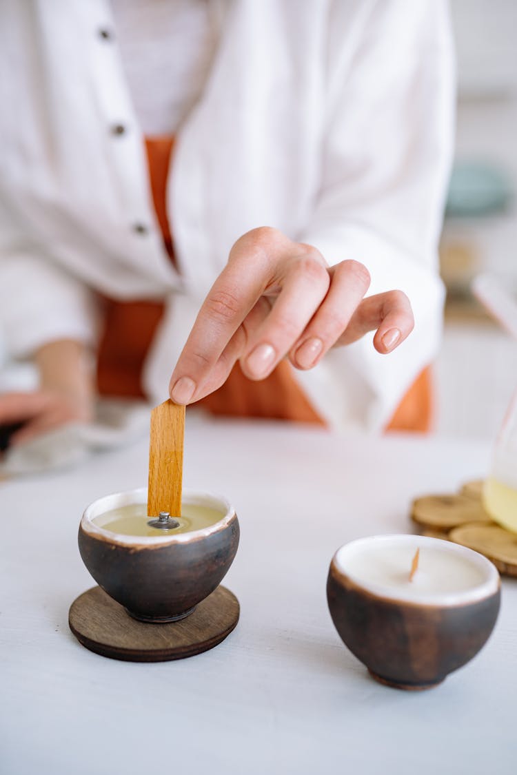 Person Putting A Candle Wick In A Cup