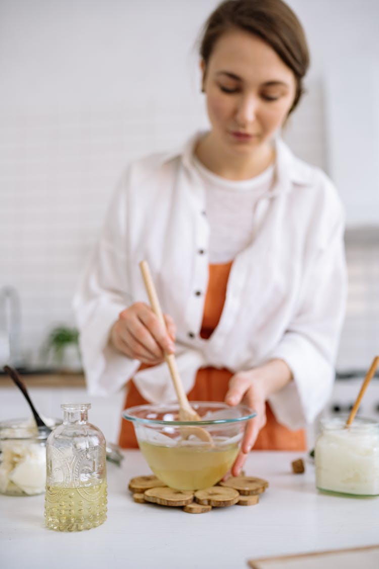 Woman Stirring Yellow Liquid On Clear Glass Bowl