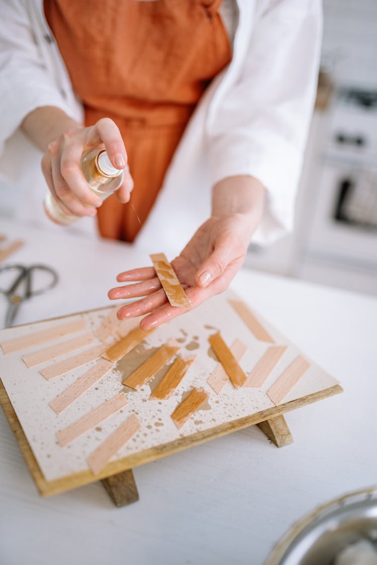 A Person Spraying Oil On Wooden Strips