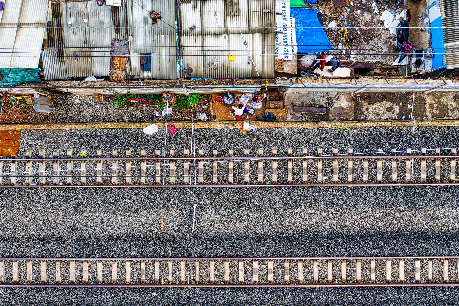 An Aerial View of a Double Train Tracks on Gray Road Near Houses