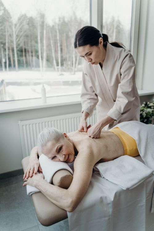 Free Senior woman enjoys a relaxing massage therapy session indoors promoting wellness. Stock Photo