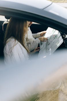 A man and woman using a map for navigation inside a car, reflecting travel plans.