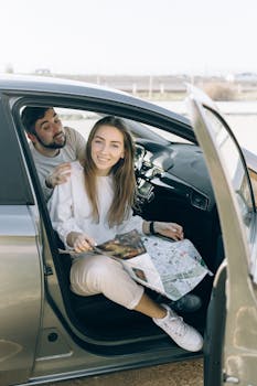 Smiling couple inside a car with map, ready for an adventurous road trip.