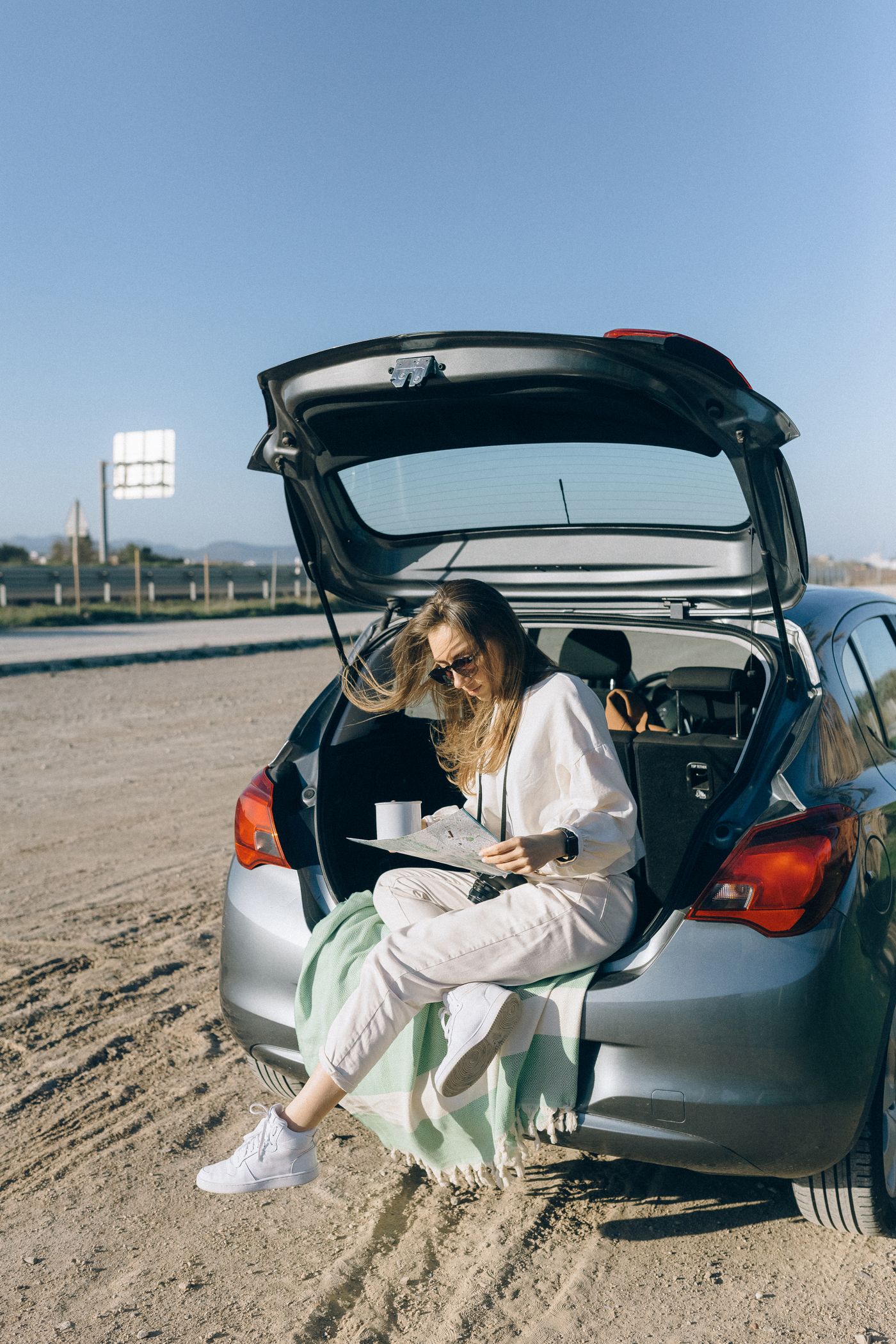 Traveller beside an open car boot during a road trip