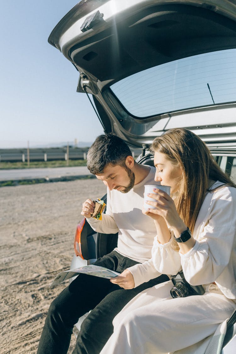 Couple Eating Snacks While Looking At A Map