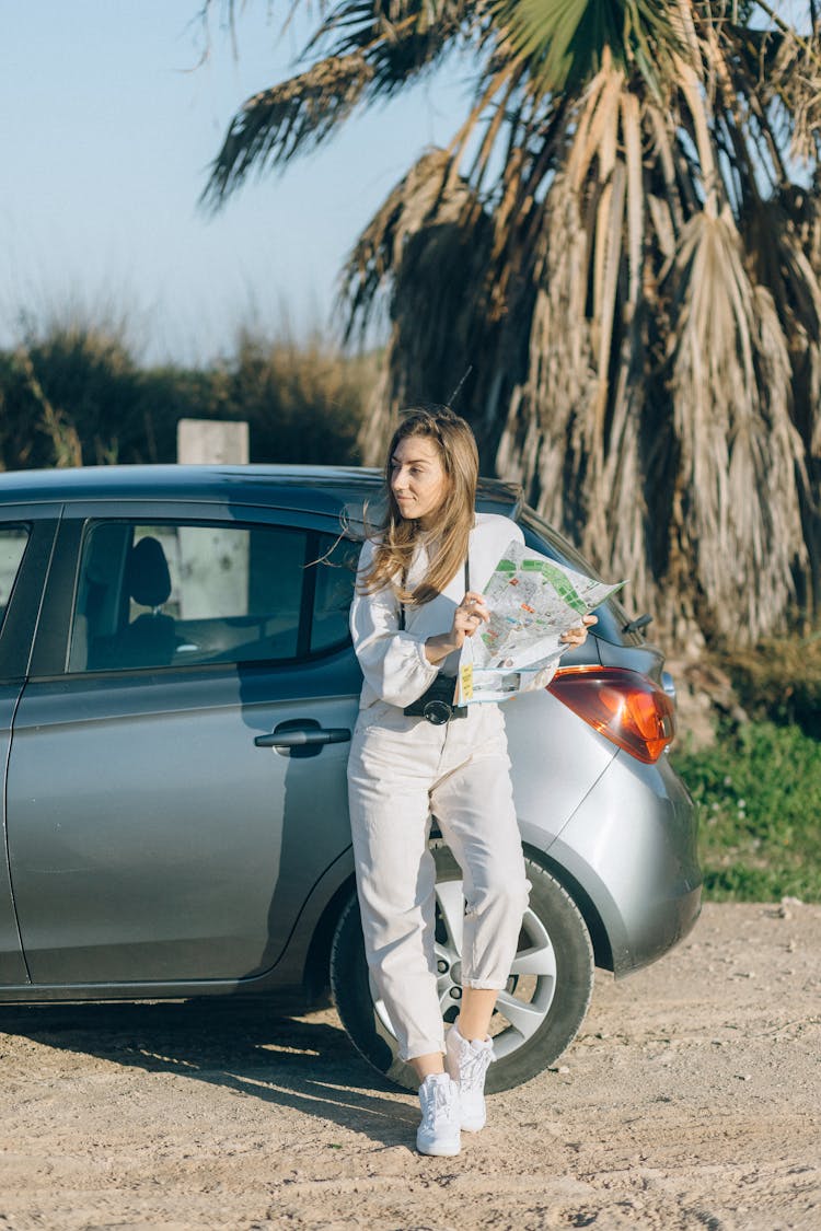 Woman Standing Against The Car Holding A Map