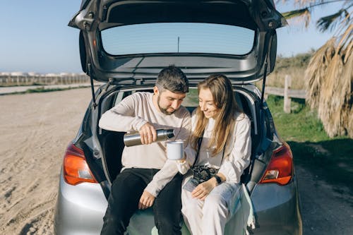 Free Man and Woman Sitting on the Car Trunk Stock Photo