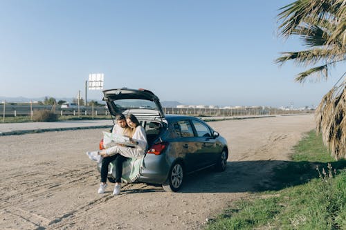 Free Couple Sitting on the Car Trunk Stock Photo