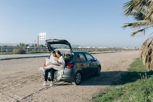 A couple sitting on car trunk exploring map during a road trip on a sunny day.