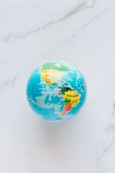 A vibrant miniature globe displaying continents on a white marble background. 7235798