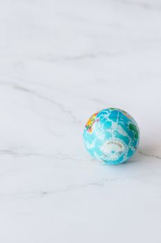 Small world globe on a white marble background, ideal for travel concepts and geography education. 7235799