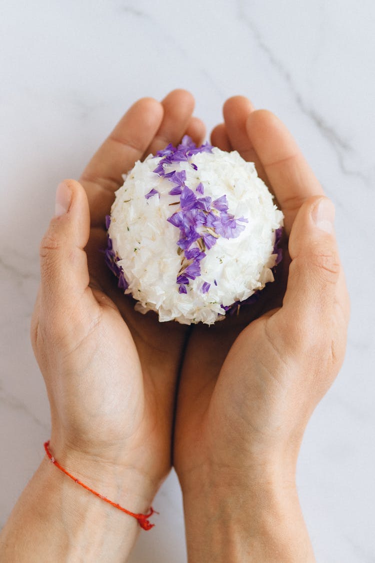 A Person Holding A Ball Covered In Flower Petals