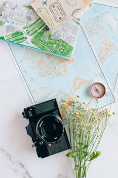 A nostalgic flatlay of a camera, maps, and compass—perfect for travel enthusiasts.