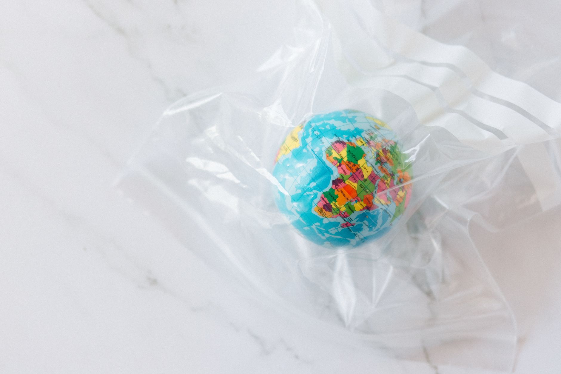 2nd Hand iPhones: How Recycling Technology and Refurbished Phones Help Britain’s Environment 2 Mini globe encased in a plastic bag symbolizing environmental concerns about plastic waste.