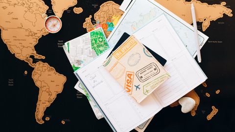 A flat lay of travel planning items on a map, featuring a compass, notebook, and guide for wanderlust enthusiasts.