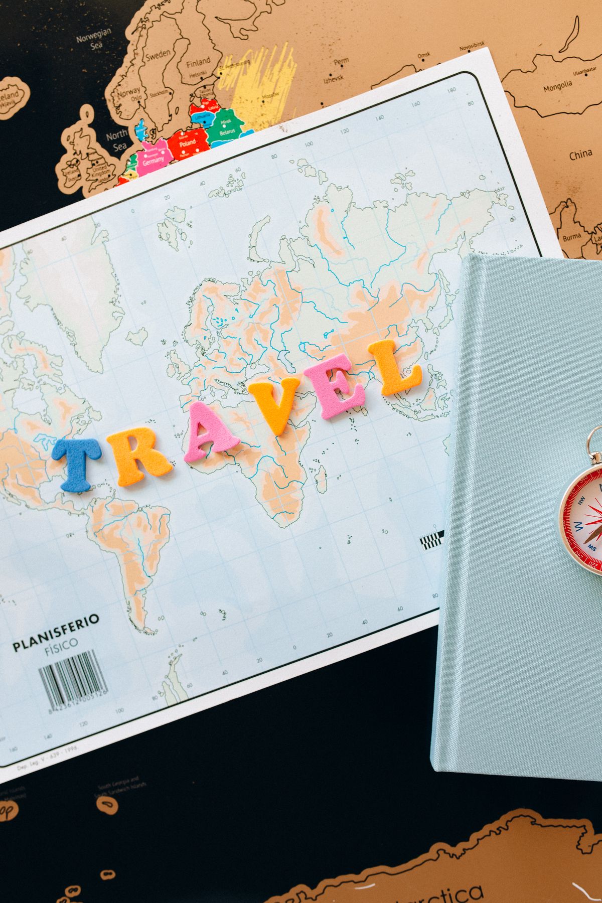 World map with colourful TRAVEL letters and a compass for planning, for a travel and geography round, trivia night party ideas