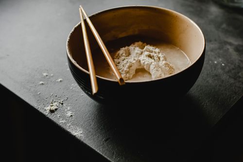 Free A bowl of flour with chopsticks, captured in a dark and moody setting, ideal for cooking themes. Stock Photo