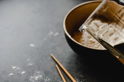 Baking ingredients setup with a bowl of flour, water, and chopsticks for a homemade recipe.