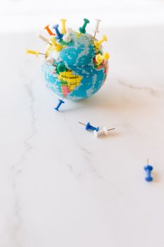 A small globe adorned with colorful pins, symbolizing travel and world exploration. 7236027