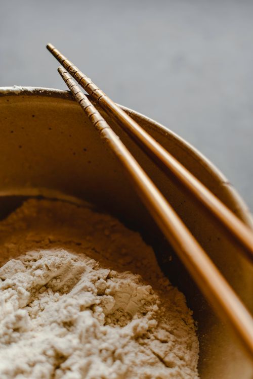 Free Close-up of chopsticks resting on a bowl of flour, perfect for culinary or food photography. Stock Photo