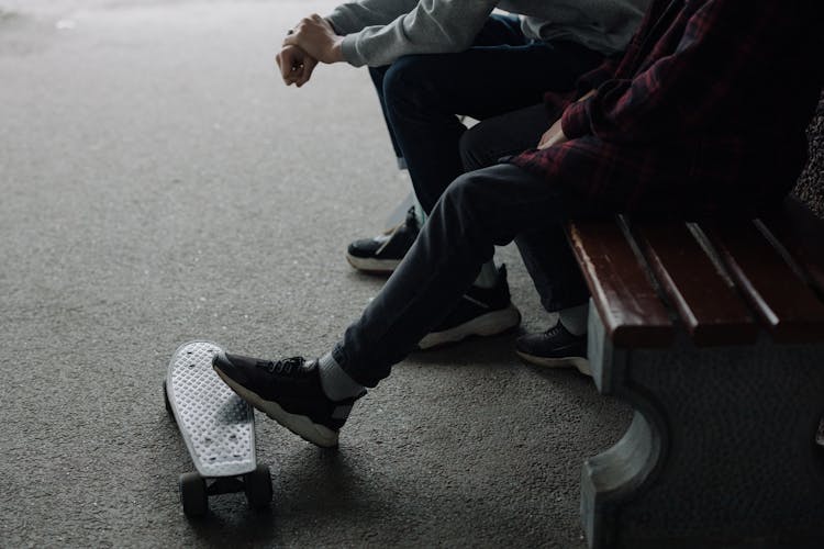 People Sitting On A Bench Stepping On Penny Board