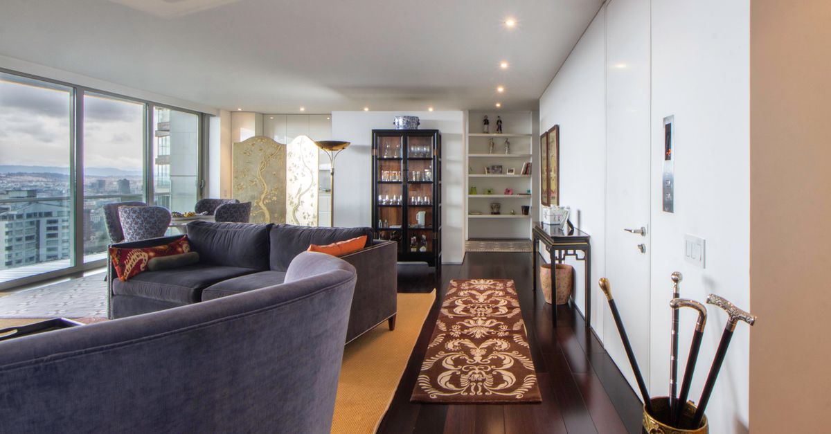 Spacious living room interior with cityscape view, modern furnishings, and decorative elements.