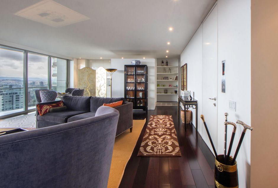 Spacious living room interior with cityscape view, modern furnishings, and decorative elements.