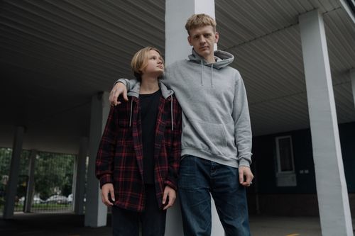 Free Two brothers in casual attire, standing under a shelter, showcase sibling bond and casual fashion. Stock Photo