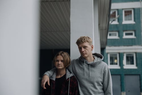 Man in Gray Hoodie Sweater Standing Beside a  Woman 