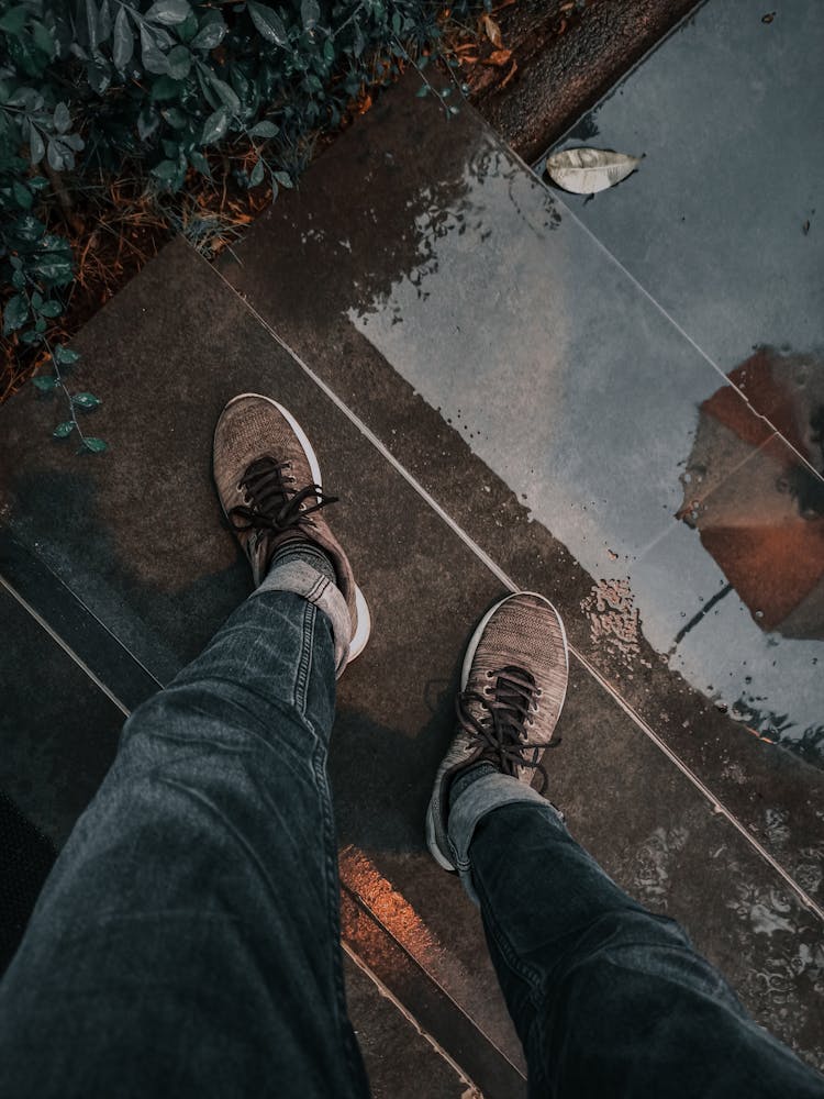 Person In Denim Jeans Standing On Wet Stairs