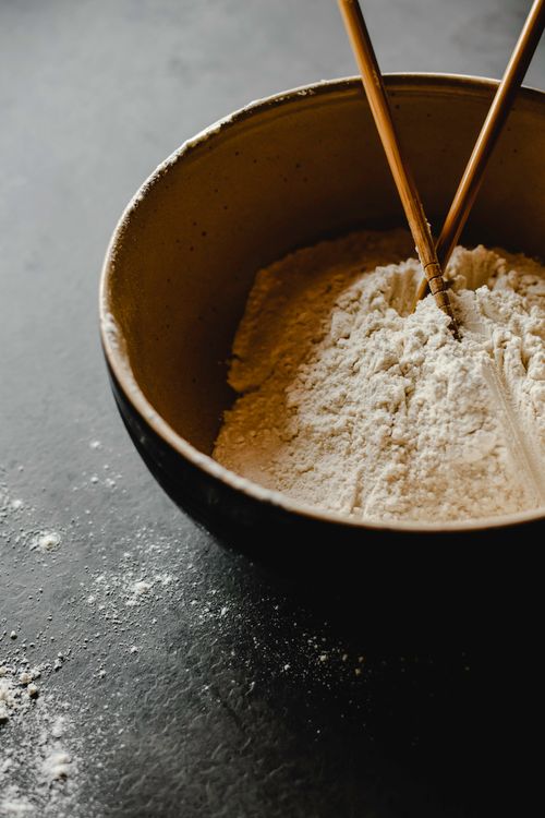 Free A close-up of flour in a ceramic bowl with chopsticks on a dark surface. Stock Photo