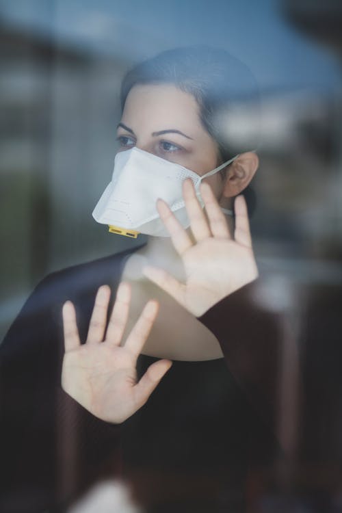 Free A Woman Behind a Glass Panel Wearing a Face Mask Stock Photo