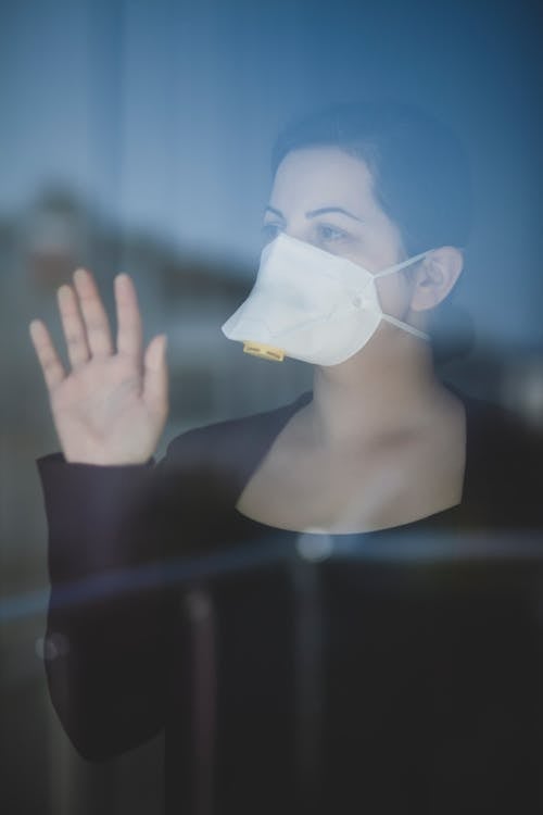Woman in Black Long Sleeve Wearing White Face Mask Waving her Hand