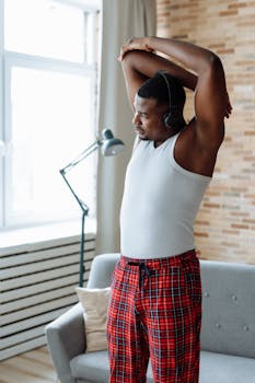 African American man in pajamas stretching at home in the morning.