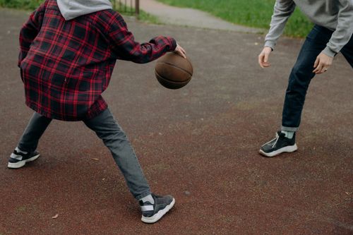 Free Two kids playing basketball on an outdoor court, enjoying a fun and active day. Stock Photo