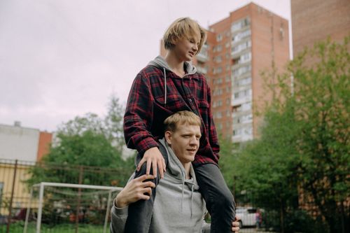 Free Two brothers bonding outdoors, one carrying the other on shoulders, showcasing joy and togetherness. Stock Photo
