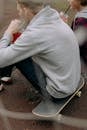 Man Wearing Gray Sweater Sitting on a Skateboard
