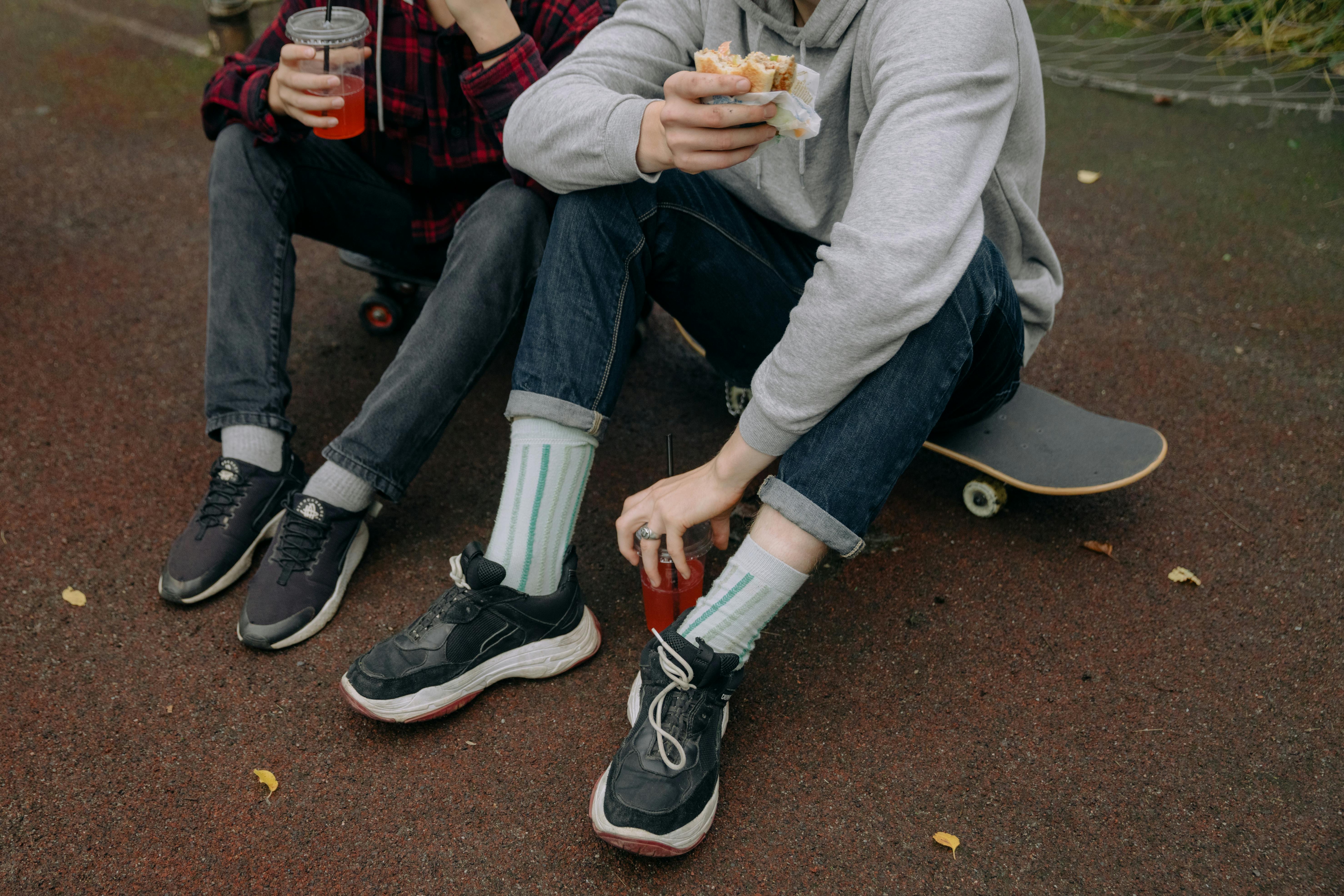 Skateboarders Sitting on Skateboards Eating and Drinking · Free Stock Photo