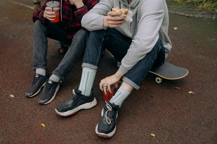 Skateboarders Sitting On Skateboards Eating And Drinking