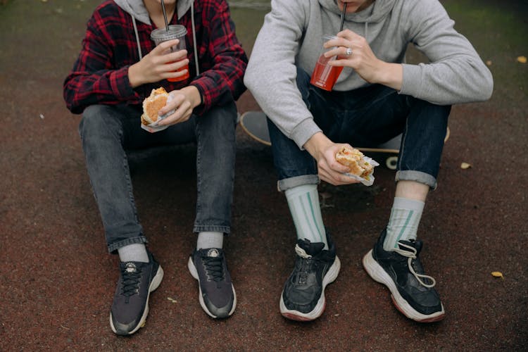 People Sitting On The Ground While Eating Snacks