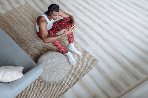 A Man Sitting on the Rug in a Wooden Floor