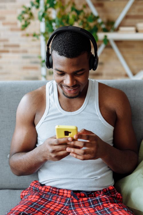 Free A man enjoys leisure time at home wearing headphones and using his smartphone. Stock Photo