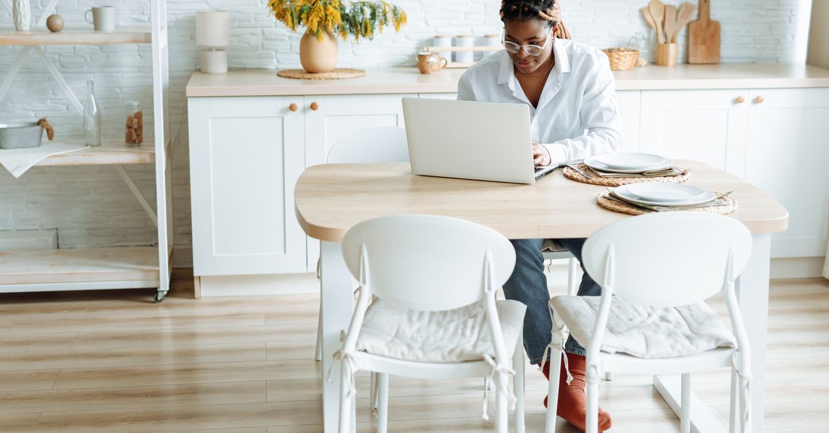person typing on laptop at kitchen table