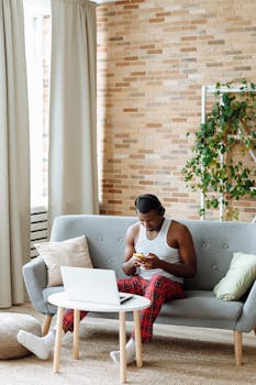 Young man using technology and relaxing on a sofa with modern decor.