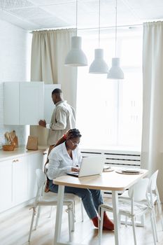An African couple engaged in daily activities in a bright and modern kitchen space.
