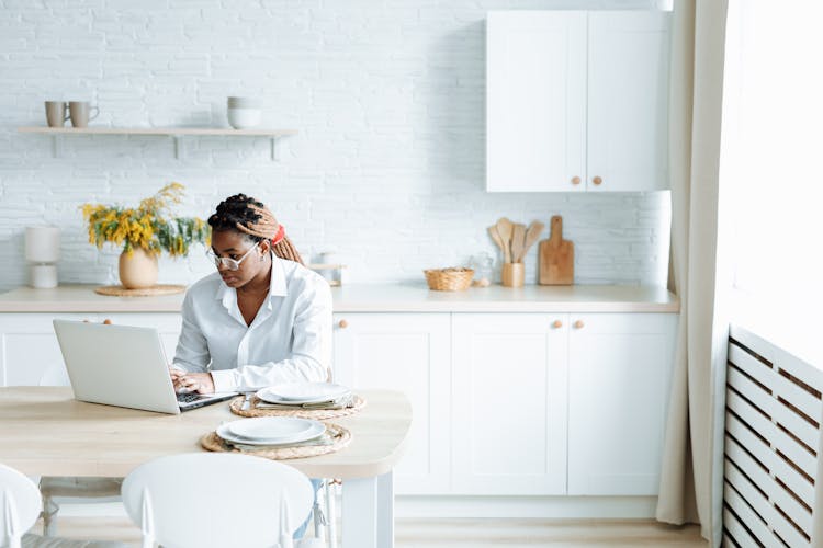 Woman Typing On A Laptop While In The Kitchen