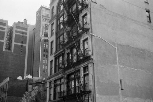 Free Grayscale photo of urban building facade with metal fire escape in an outdoor city setting. Stock Photo