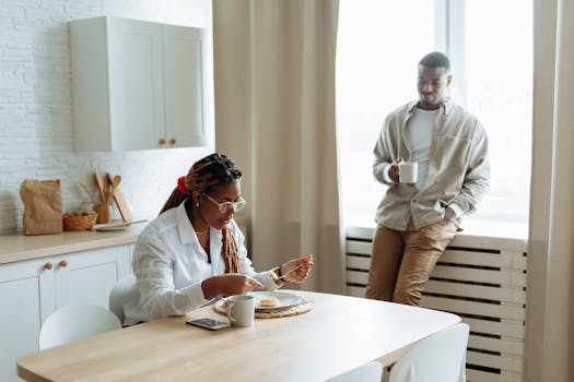 An adult couple enjoying breakfast in a modern kitchen with natural light.