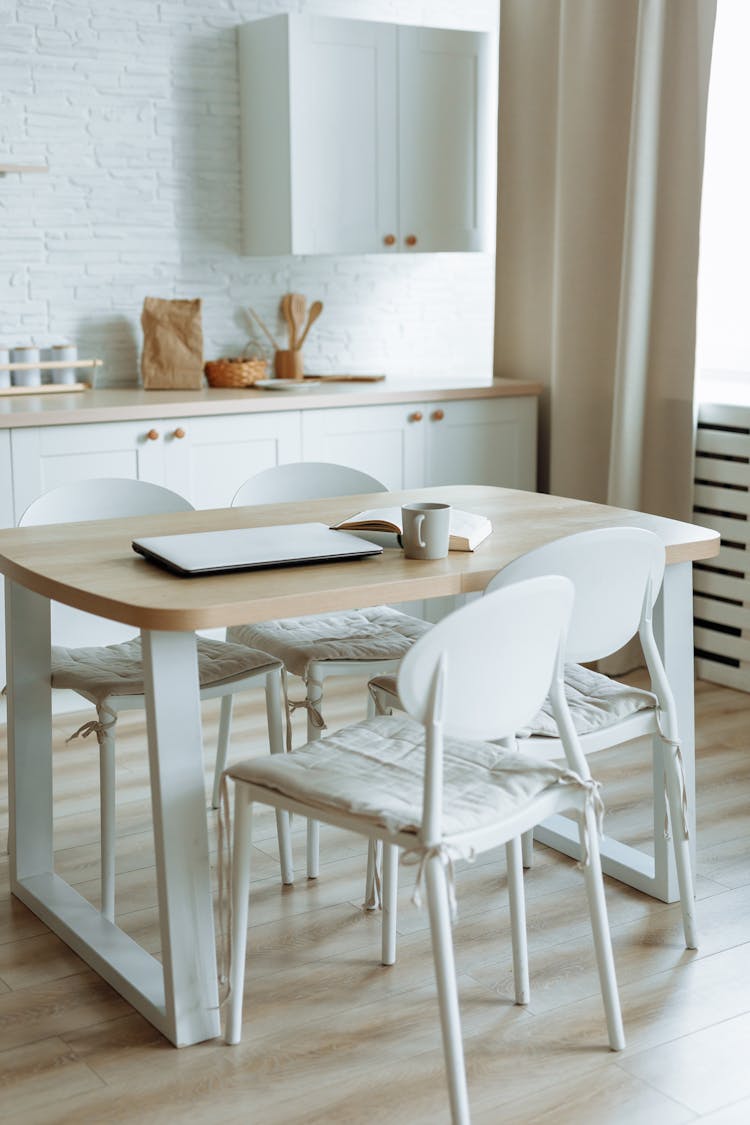 A Book Beside Mug And Laptop On Wooden Table