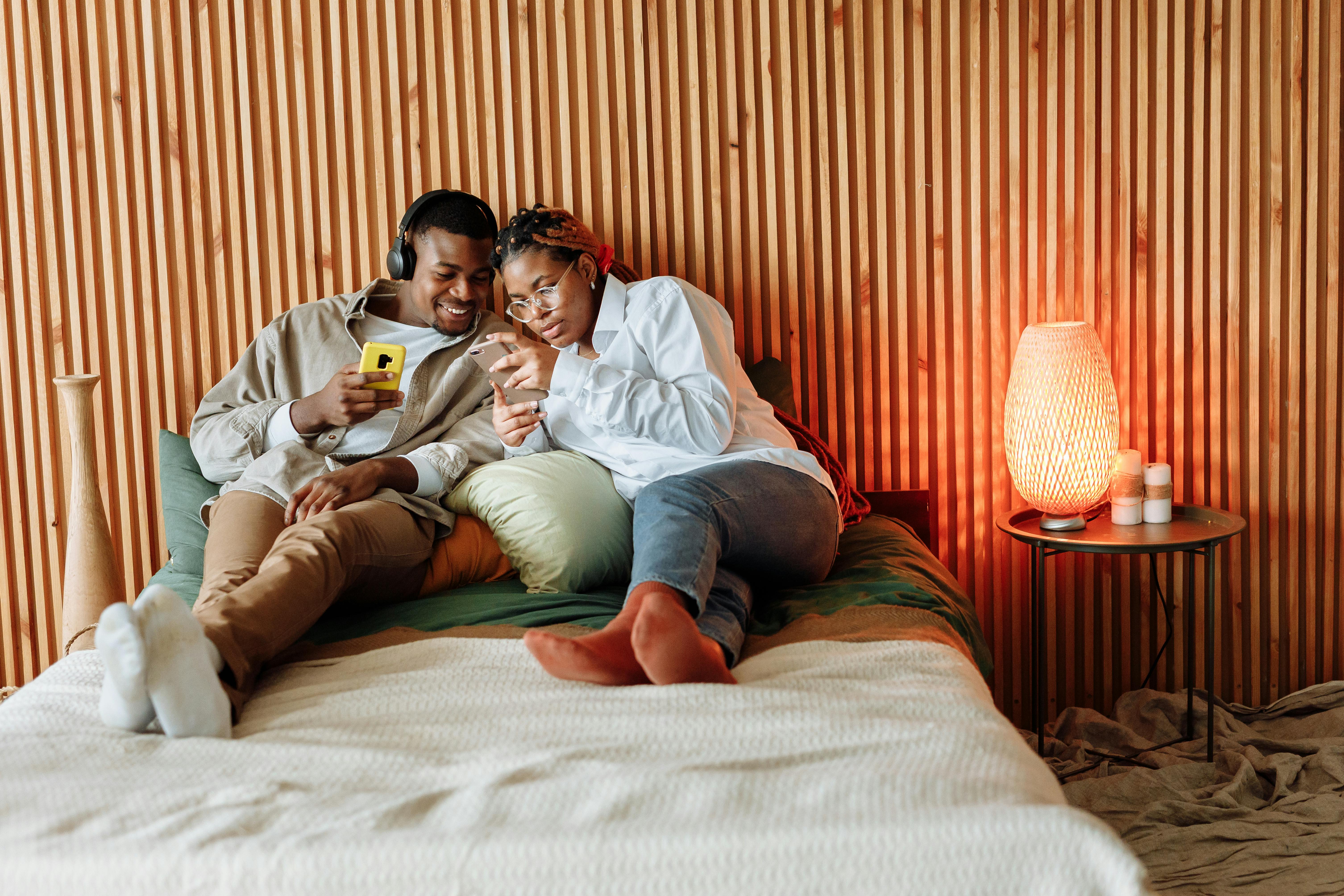 Couple enjoying a cozy moment with smartphones in a modern bedroom setting.